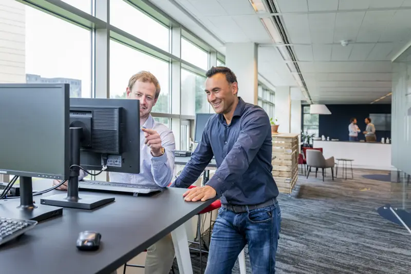 Twee collega's van TMC overleggen bij een werkplek